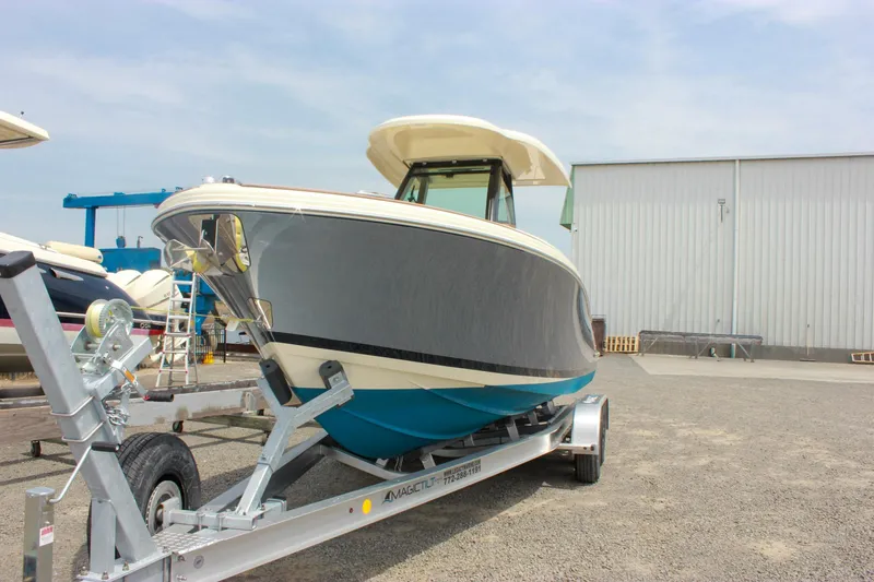 Slide: The Image of 2024 Chris-Craft Catalina 24 boat on trailer, parked outdoors near a warehouse. - 6