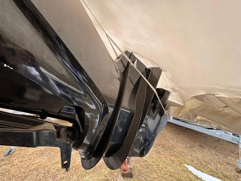 Slide: The Image of Close-up of a 1997 Mako 191 boat undercarriage, showing black components and tarp cover. - 2