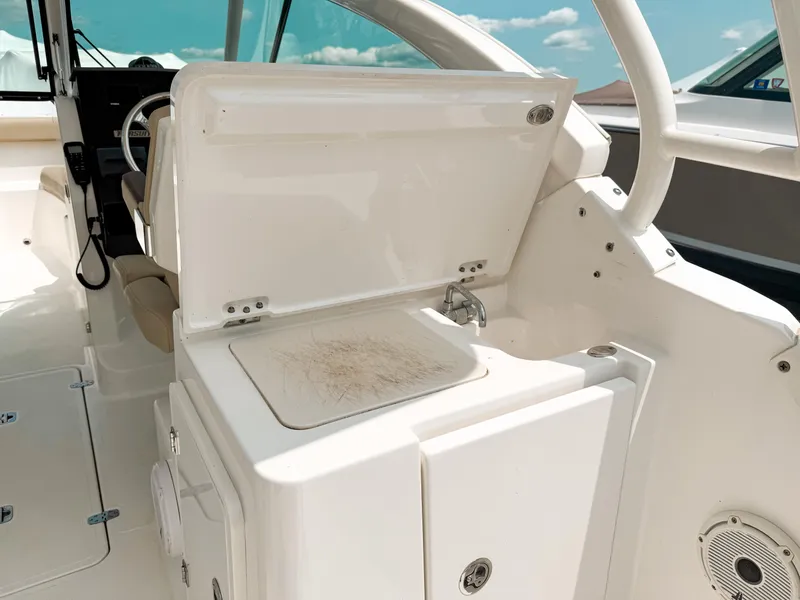 Slide: The Image of 2020 Pursuit DC 266 Dual Console boat interior with open storage compartment and sink. - 10