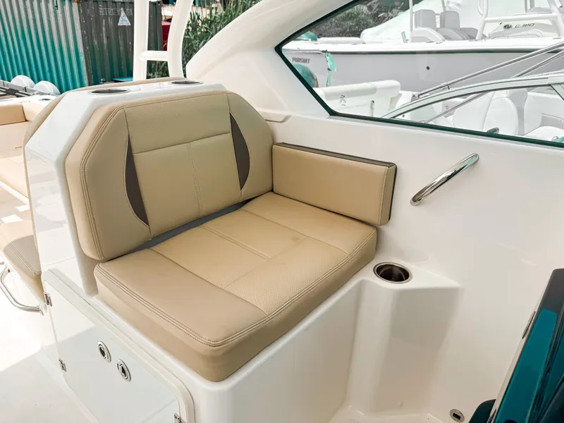 Slide: The Image of 2020 Pursuit DC 266 Dual Console boat interior with beige seating and cup holder. - 11