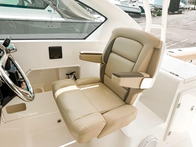Slide: The Image of Luxurious helm seat on 2020 Pursuit DC 266 Dual Console boat, featuring beige upholstery. - 12