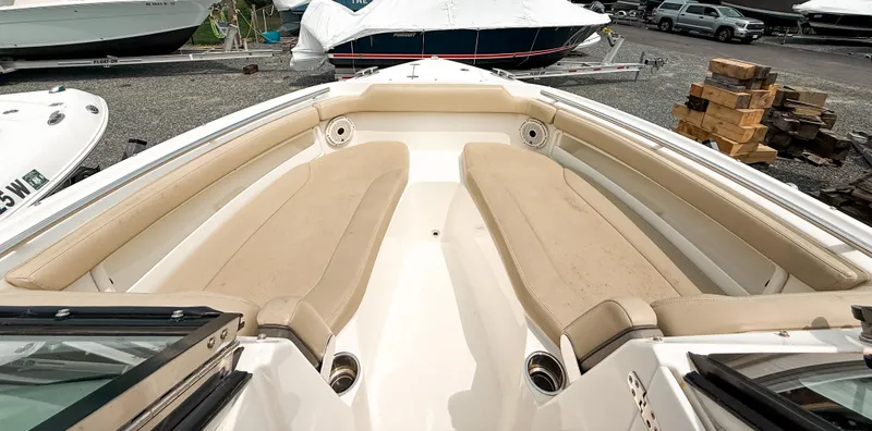 Slide: The Image of 2020 Pursuit DC 266 Dual Console boat with beige seating in a marina setting. - 15