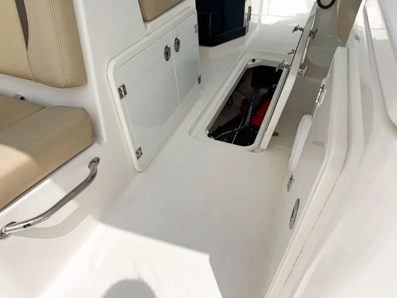 Slide: The Image of 2020 Pursuit DC 266 Dual Console interior with open storage compartment and beige seating. - 27