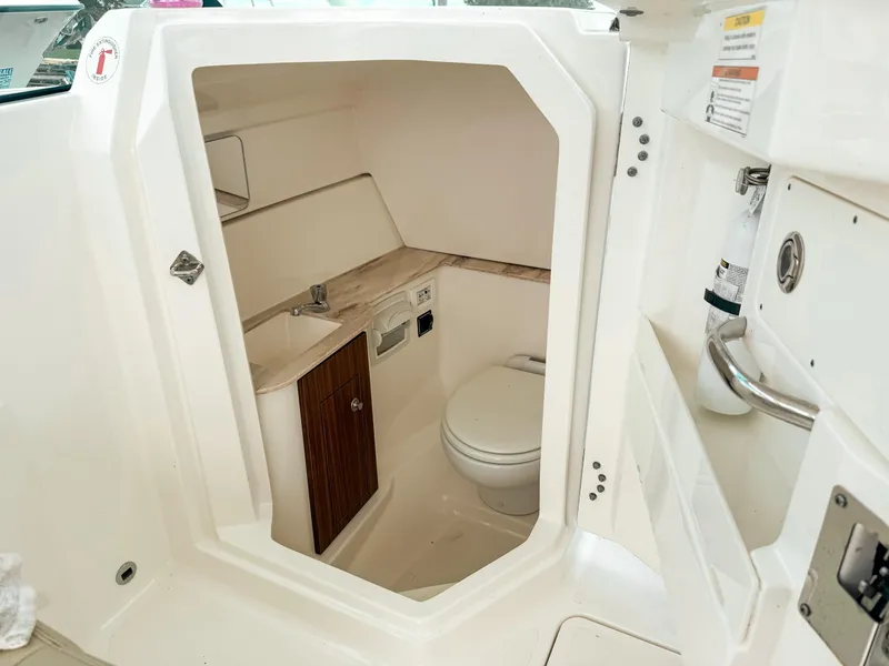 Slide: The Image of 2020 Pursuit DC 266 Dual Console boat interior with compact bathroom and toilet. - 28