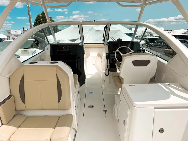 Slide: The Image of 2020 Pursuit DC 266 Dual Console boat interior with beige seating and modern helm. - 6