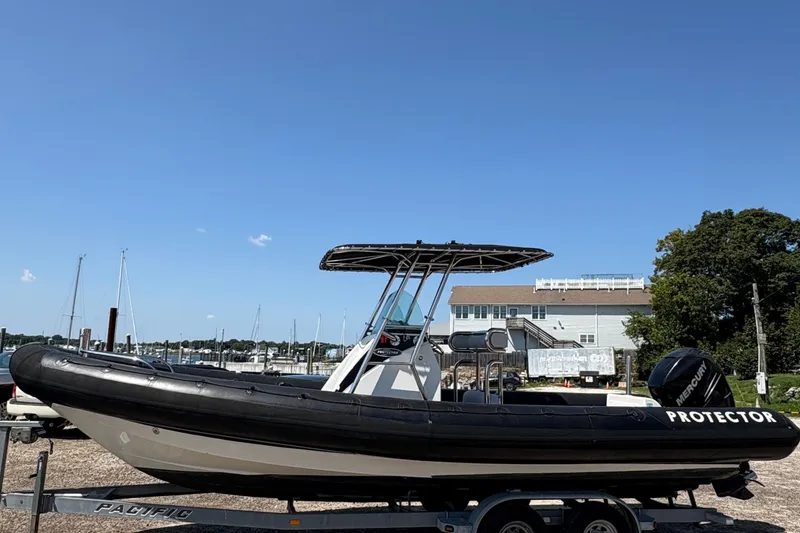 Slide: The Image of 2013 Protector 25 Center Console boat on trailer, marina background, clear sky. - 5