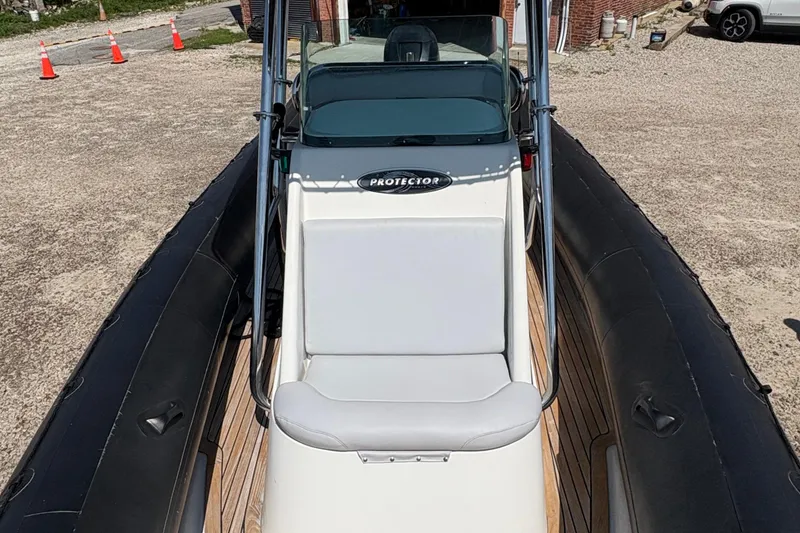 Slide: The Image of 2013 Protector 25 Center Console boat with black inflatable sides and white seating. - 8