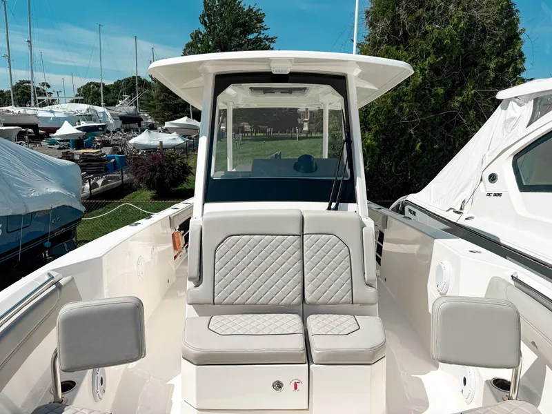 Slide: The Image of 2024 Pursuit S 288 Sport boat with cushioned seating and sleek design in a marina setting. - 15