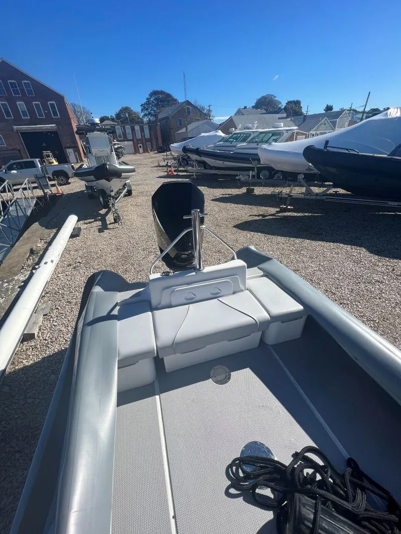 Slide: The Image of 2023 Protector 250 Chase boat on gravel lot, surrounded by other vessels under clear blue sky. - 3
