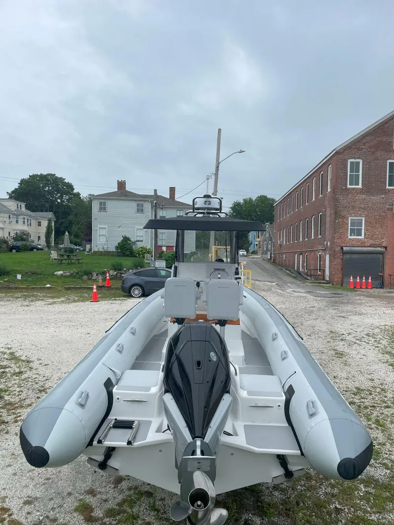 Slide: The Image of 2023 Protector 250 Chase boat on gravel lot, overcast sky, brick building background. - 7