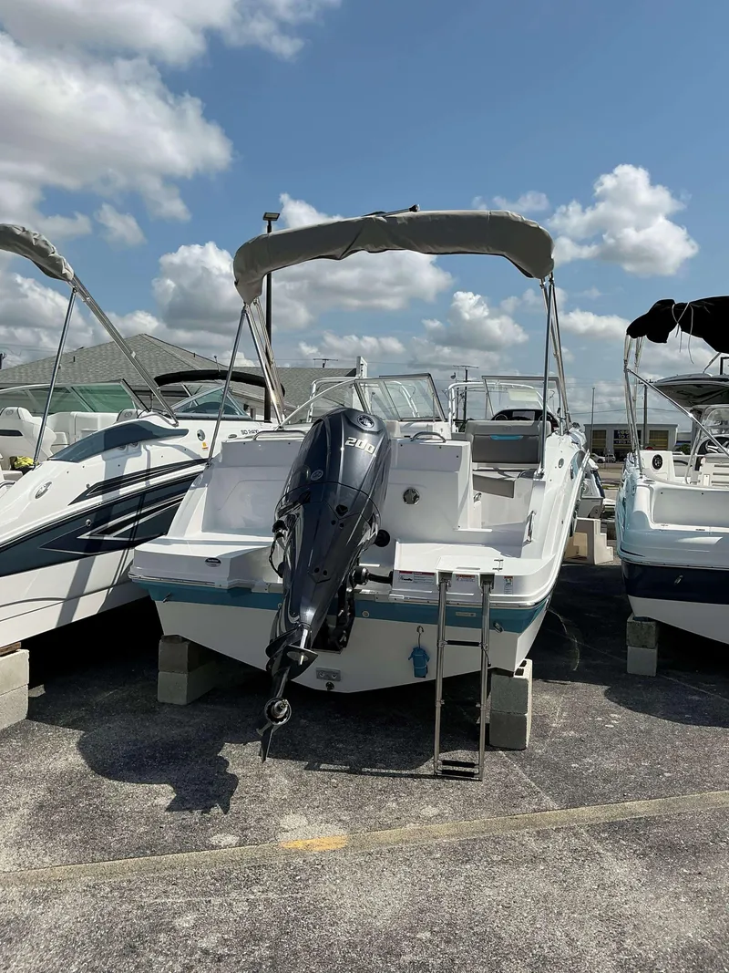 Slide: The Image of 2025 Hurricane 235 SD boat with outboard motor, parked on concrete blocks under a blue sky. - 5