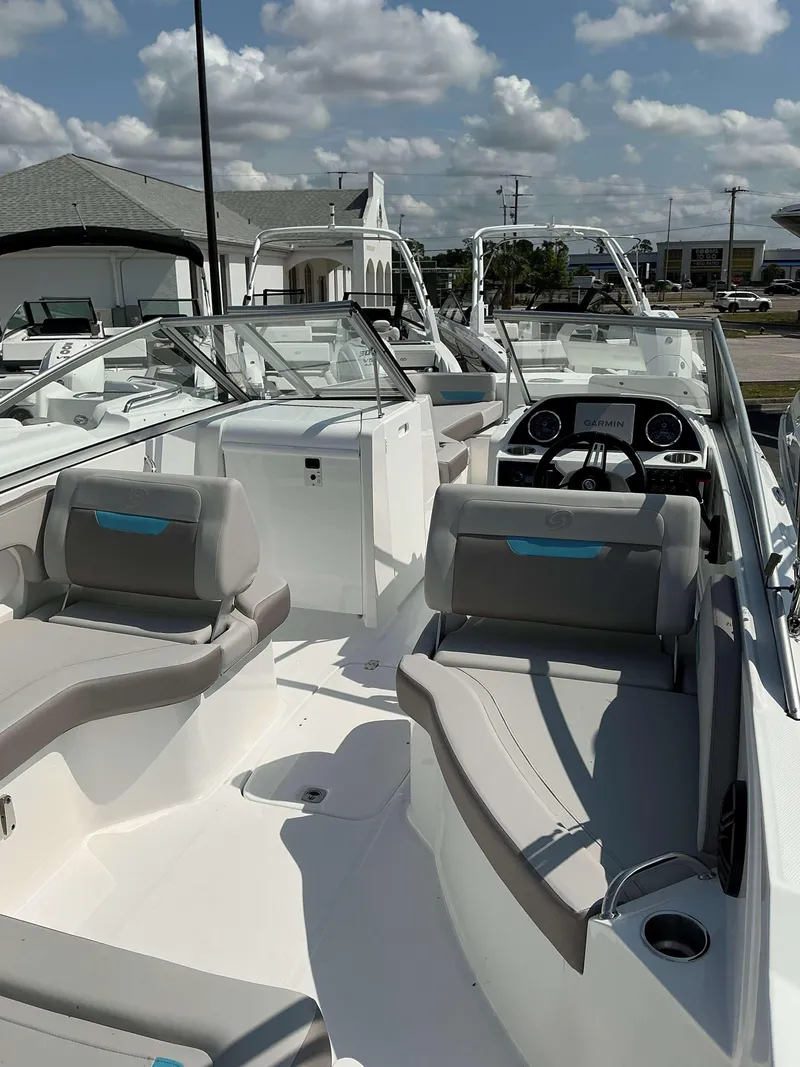 Slide: The Image of 2025 Hurricane 235 SD boat interior with modern seating and dashboard under a cloudy sky. - 7
