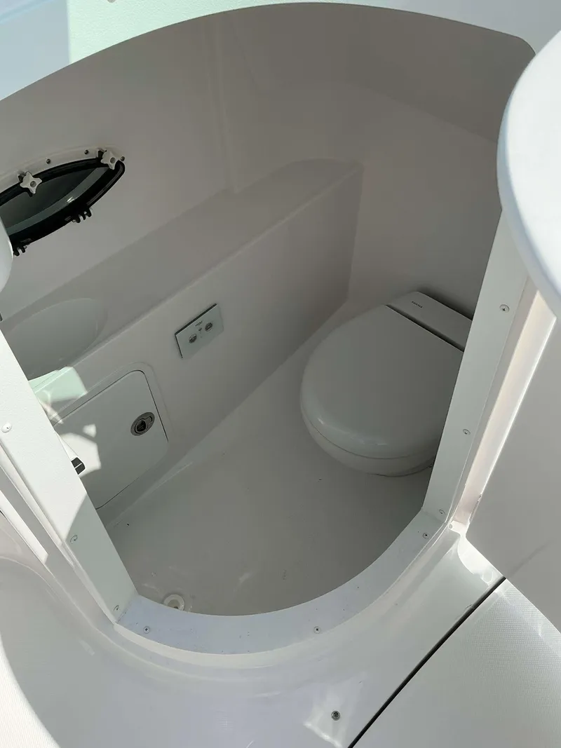 Slide: The Image of 2025 Hurricane 2400 SD boat interior with compact marine toilet and porthole. - 11