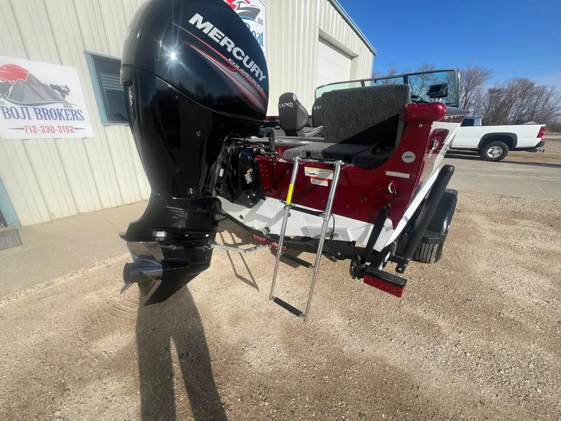 Slide: The Image of 2014 Lund 1875 Crossover XS boat with Mercury outboard motor and ladder, parked outside. - 10
