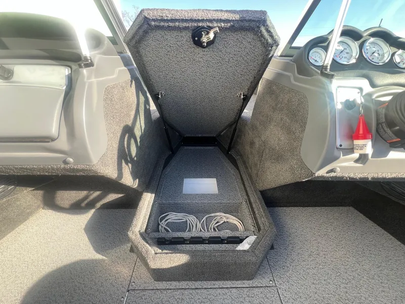Slide: The Image of 2014 Lund 1875 Crossover XS boat interior with open storage compartment and dashboard gauges. - 13