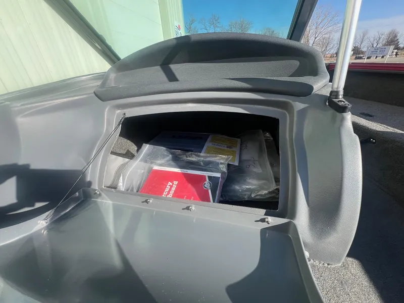 Slide: The Image of Open storage compartment in a 2014 Lund 1875 Crossover XS boat, containing manuals and documents. - 18