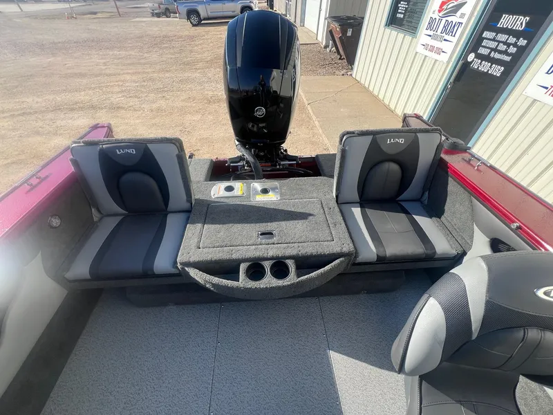 Slide: The Image of 2014 Lund 1875 Crossover XS boat interior with seating and motor, parked outside a building. - 21