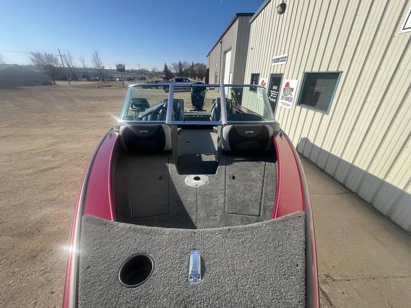 Slide: The Image of 2014 Lund 1875 Crossover XS boat with red exterior, parked outdoors near a building. - 5