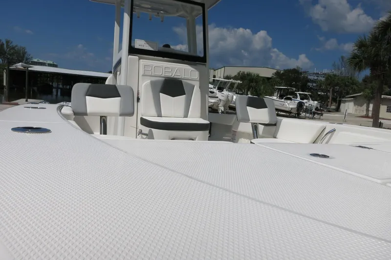 Slide: The Image of 2025 Robalo 246 Cayman boat with white seating and console, docked under a blue sky. - 14
