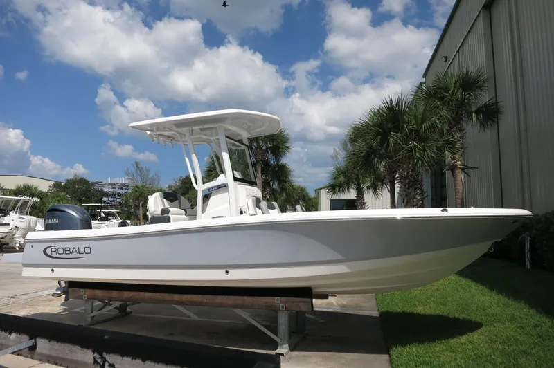 Slide: The Image of 2025 Robalo 246 Cayman boat displayed outdoors near palm trees. - 2