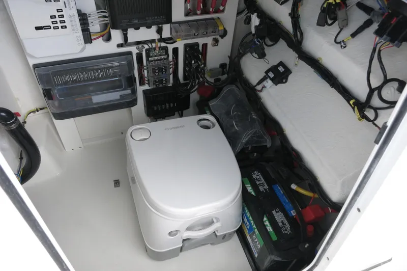 Slide: The Image of 2024 Crevalle 26 HCO boat interior with electrical components and portable toilet. - 30