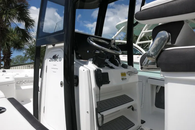 Slide: The Image of 2024 Crevalle 26 HCO boat console with steering wheel and controls, under a clear blue sky. - 6