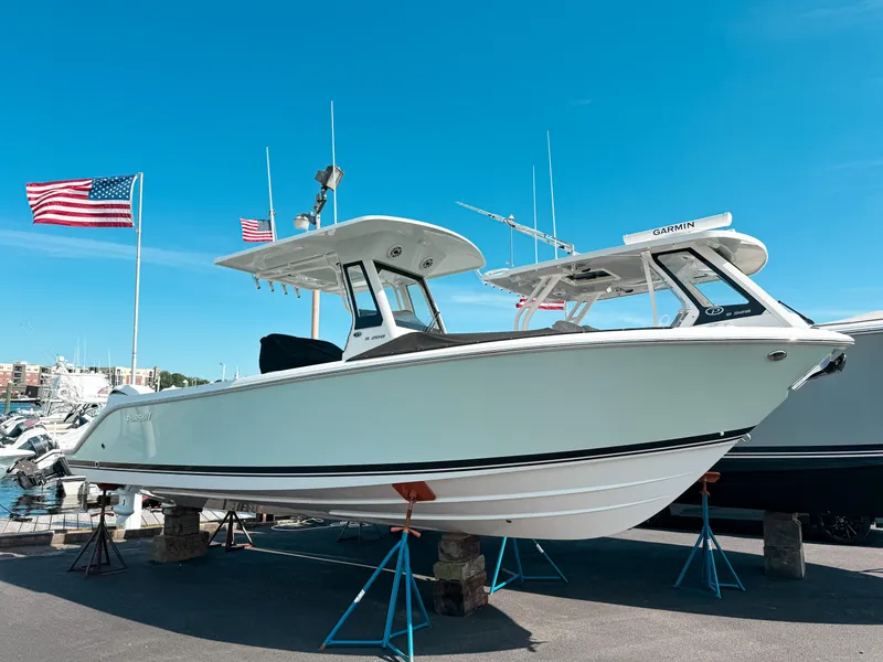 The Image of 2025 Pursuit S 268 Sport boat displayed on stands with American flags in the background. - 0