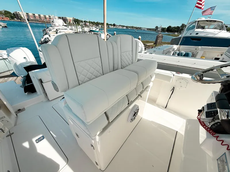 Slide: The Image of 2025 Pursuit S 268 Sport boat with luxurious seating, docked by a scenic waterfront. - 13