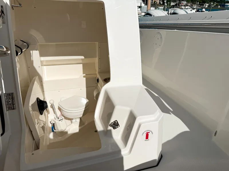 Slide: The Image of 2025 Pursuit S 268 Sport boat interior with compact marine toilet and storage shelves. - 20