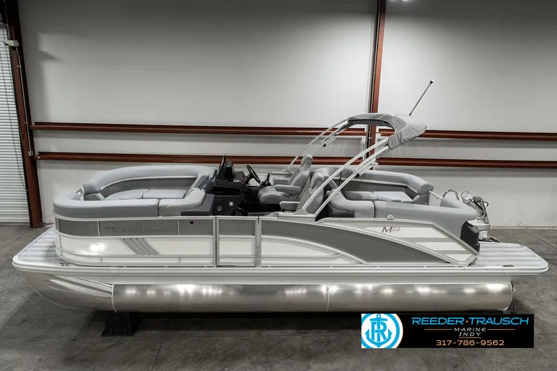 Slide: The Image of 2025 Bennington 22 MFB pontoon boat in a showroom, featuring sleek design and comfortable seating. - 1