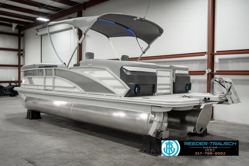 Slide: The Image of 2025 Bennington 22 MFB pontoon boat in a warehouse, featuring sleek design and canopy. - 6