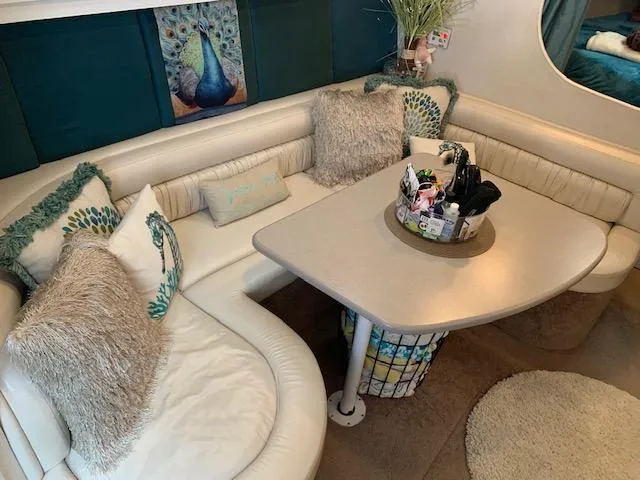 Slide: The Image of 1994 Silverton 34 Express yacht interior with cozy seating, decorative pillows, and a central table. - 16