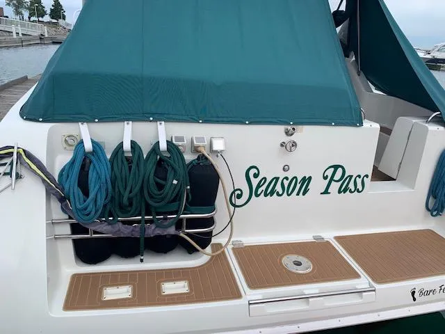 Slide: The Image of 1994 Silverton 34 Express boat named "Season Pass" docked with teal cover and coiled ropes. - 3