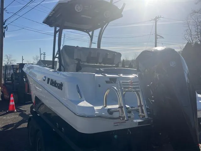 Slide: The Image of 2021 Wellcraft 222 Fisherman boat with outboard motor, parked outdoors under sunlight. - 2