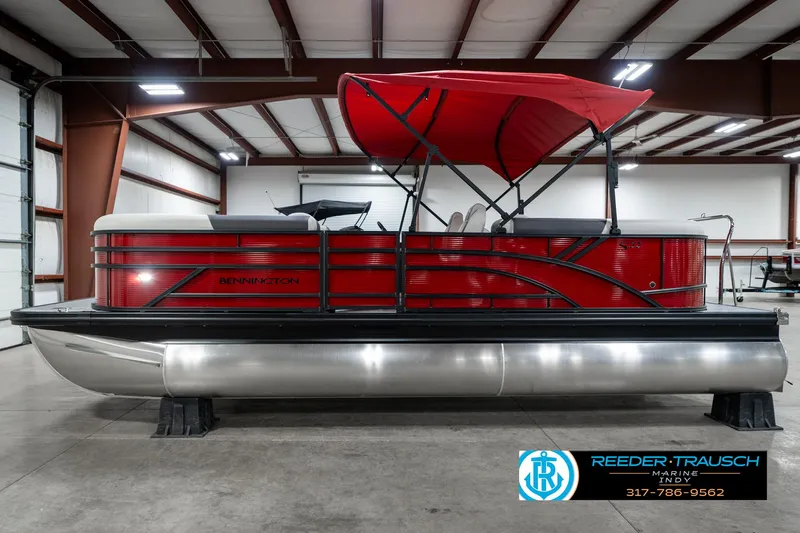 Slide: The Image of 2025 Bennington 22 SSR pontoon boat with red canopy in a warehouse setting. - 11