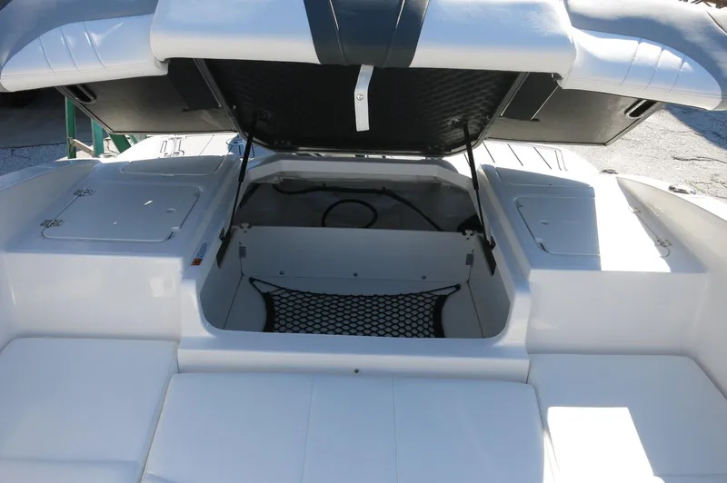 Slide: The Image of 2025 Chaparral 21 SSi Outboard boat with open storage compartment and cushioned seating. - 18