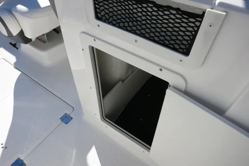 Slide: The Image of 2025 Chaparral 21 SSi Outboard boat storage compartment with open door and netted pocket. - 38