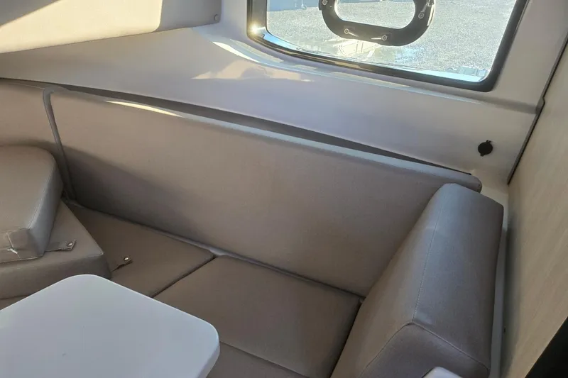 Slide: The Image of Interior of 2026 Hurricane SunDeck 3200 OB, featuring comfortable seating and a window view. - 62