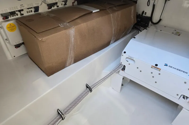 Slide: The Image of 2026 Hurricane SunDeck 3200 OB storage area with Seakeeper stabilizer and cardboard box. - 71