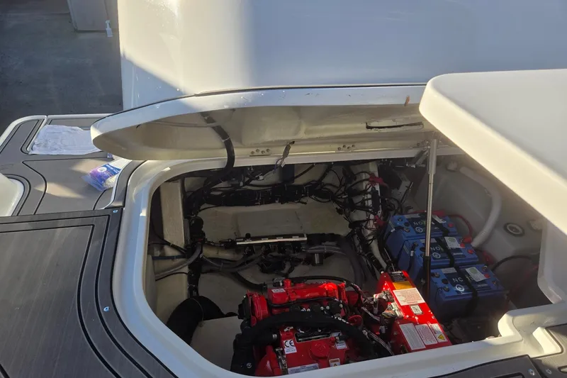 Slide: The Image of Open engine compartment of 2026 Hurricane SunDeck 3200 OB boat, showing batteries and wiring. - 75