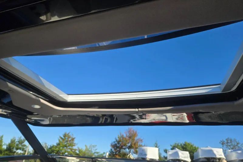 Slide: The Image of 2026 Hurricane SunDeck 3200 OB boat with open sunroof under clear blue sky. - 84