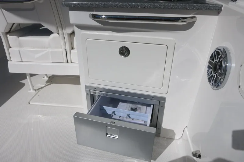 Slide: The Image of 2025 Chaparral 280 OSX Bowrider interior with open storage compartment and speaker. - 23