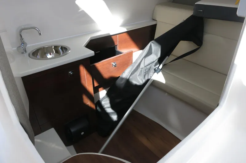 Slide: The Image of 2025 Chaparral 280 OSX Bowrider interior with sink, seating, and storage. - 41