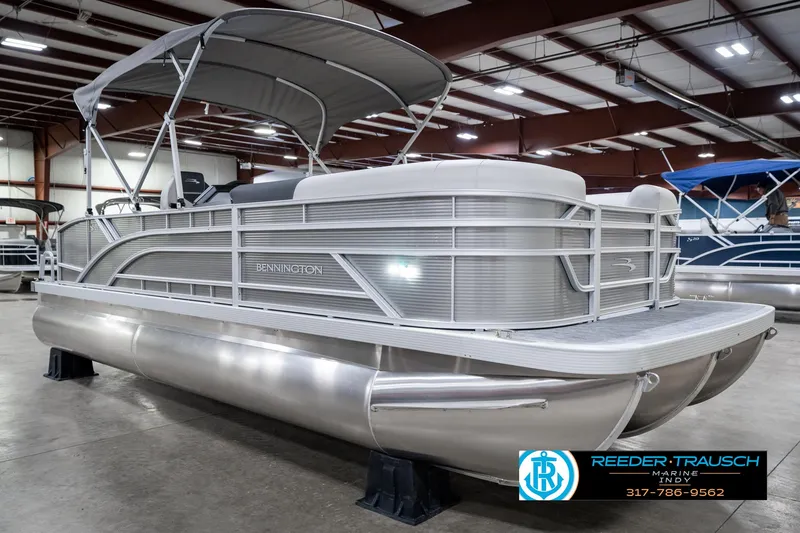 Slide: The Image of 2025 Bennington 22 SSB pontoon boat in showroom, featuring sleek design and canopy. - 6