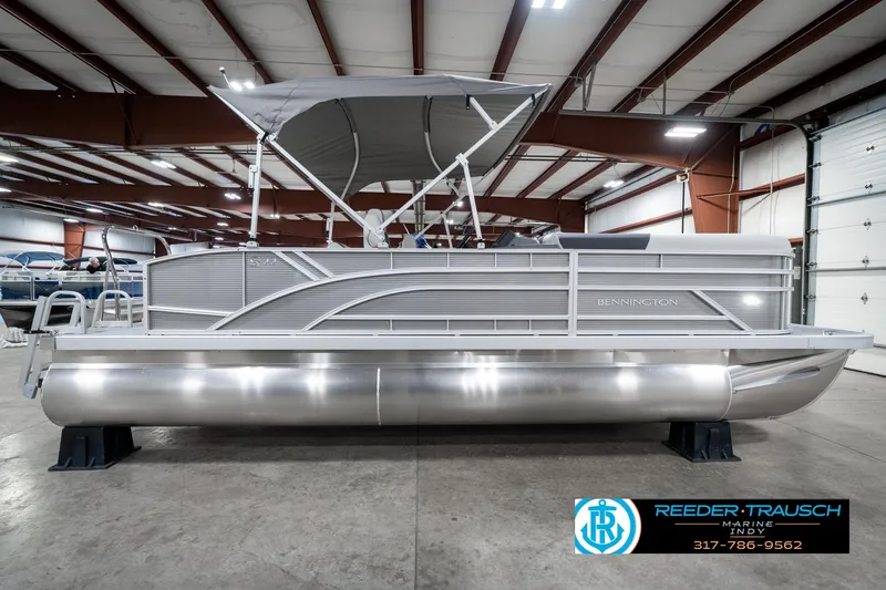 Slide: The Image of 2025 Bennington 22 SSB pontoon boat in showroom, featuring sleek design and canopy. - 7