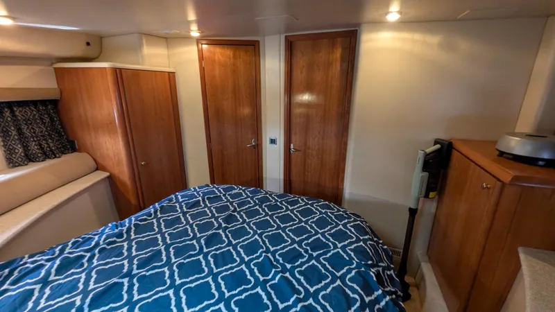 Slide: The Image of 2004 Meridian 408 Motor Yacht bedroom with blue patterned bedding and wooden cabinetry. - 15