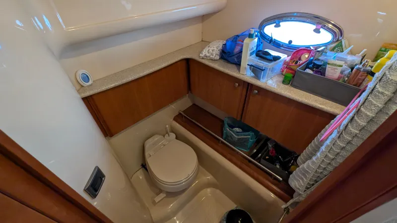 Slide: The Image of 2004 Meridian 408 Motor Yacht bathroom with toilet, storage cabinets, and porthole window. - 37
