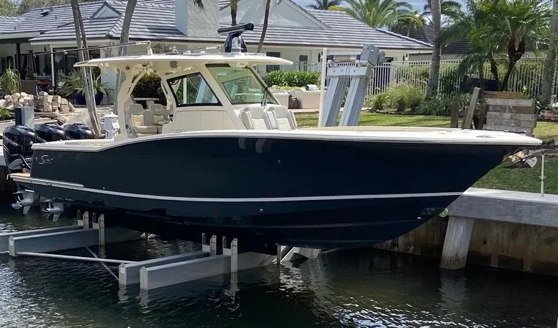 The Image of 2021 Scout 355 LXF boat docked on a lift near a waterfront home. - 0