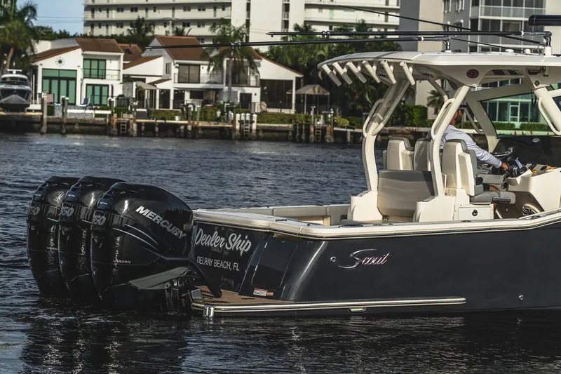 Slide: The Image of 2021 Scout 355 LXF boat with triple Mercury engines on a calm waterfront. - 12