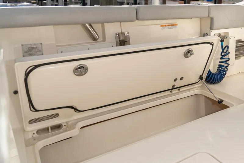 Slide: The Image of 2021 Scout 355 LXF boat storage compartment with open lid and coiled hose. - 37